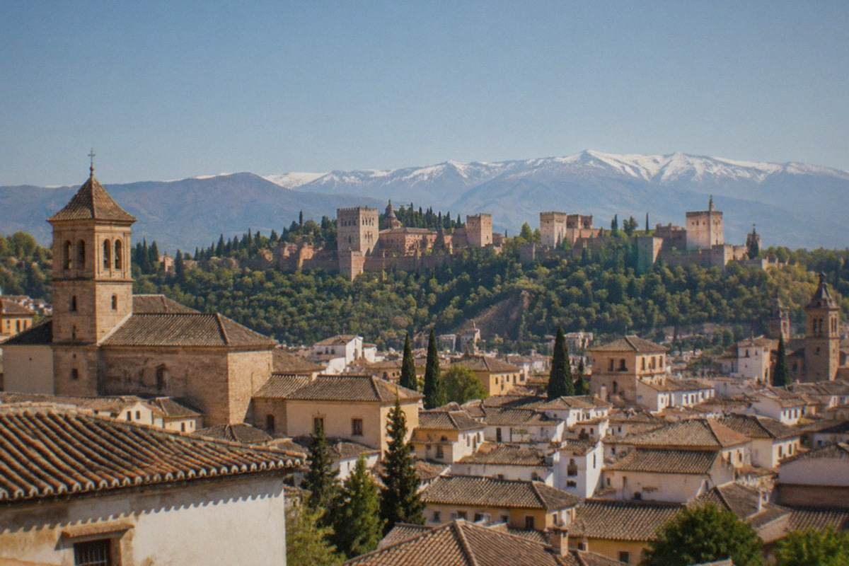 Granada's old town rooftops and the Alhambra hill seen together under a clear Andalusian sky.