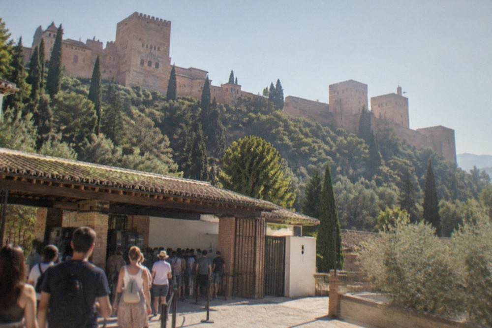 Visitors queuing at the Alhambra entrance pavilion with the ticket machines and gates in view