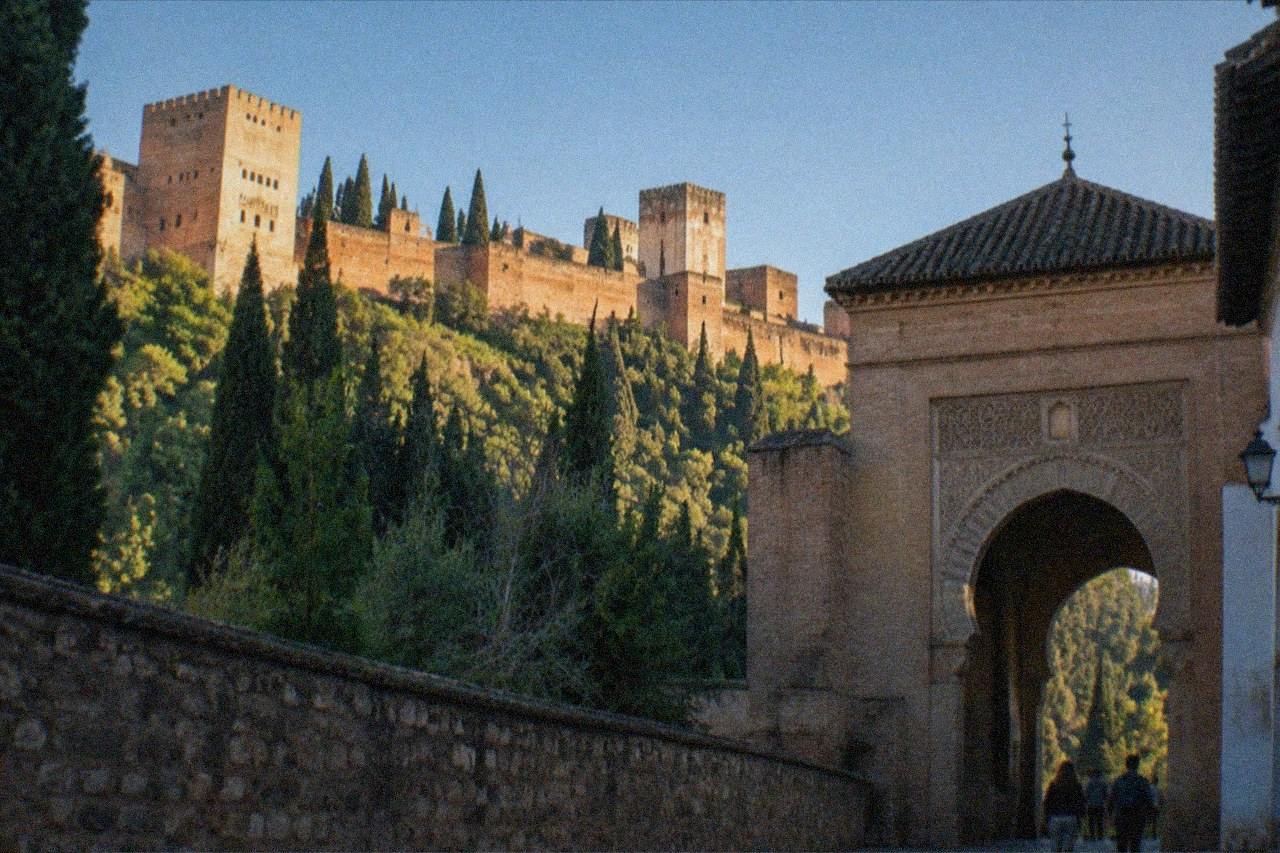 The ornate arched gate of the Alhambra complex in Granada under a clear sky