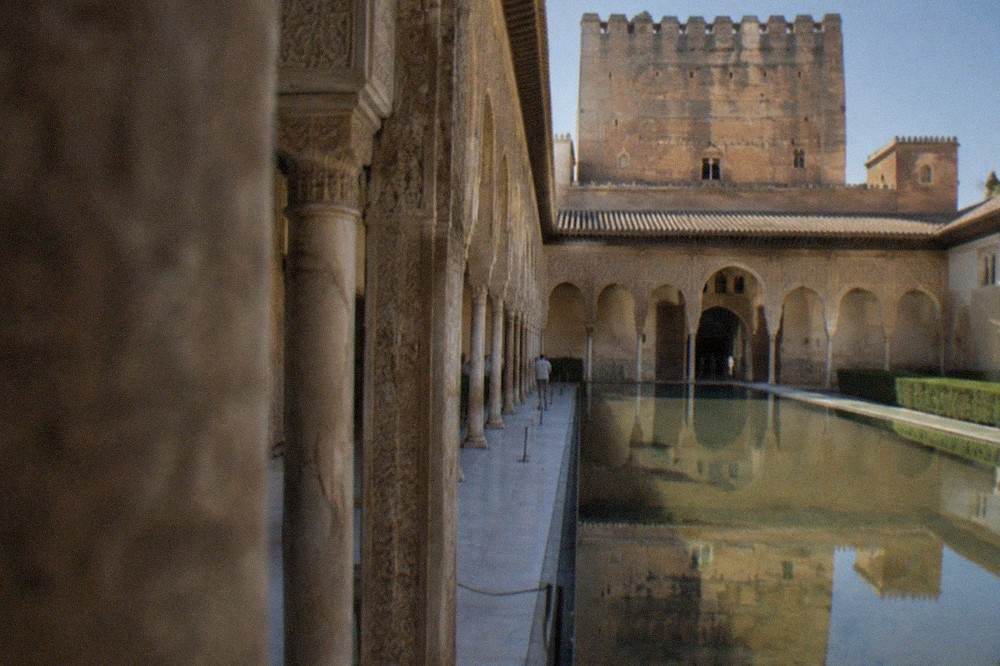 The arched courtyard and reflecting pool of the Nasrid Palaces inside the Alhambra, with carved stucco walls