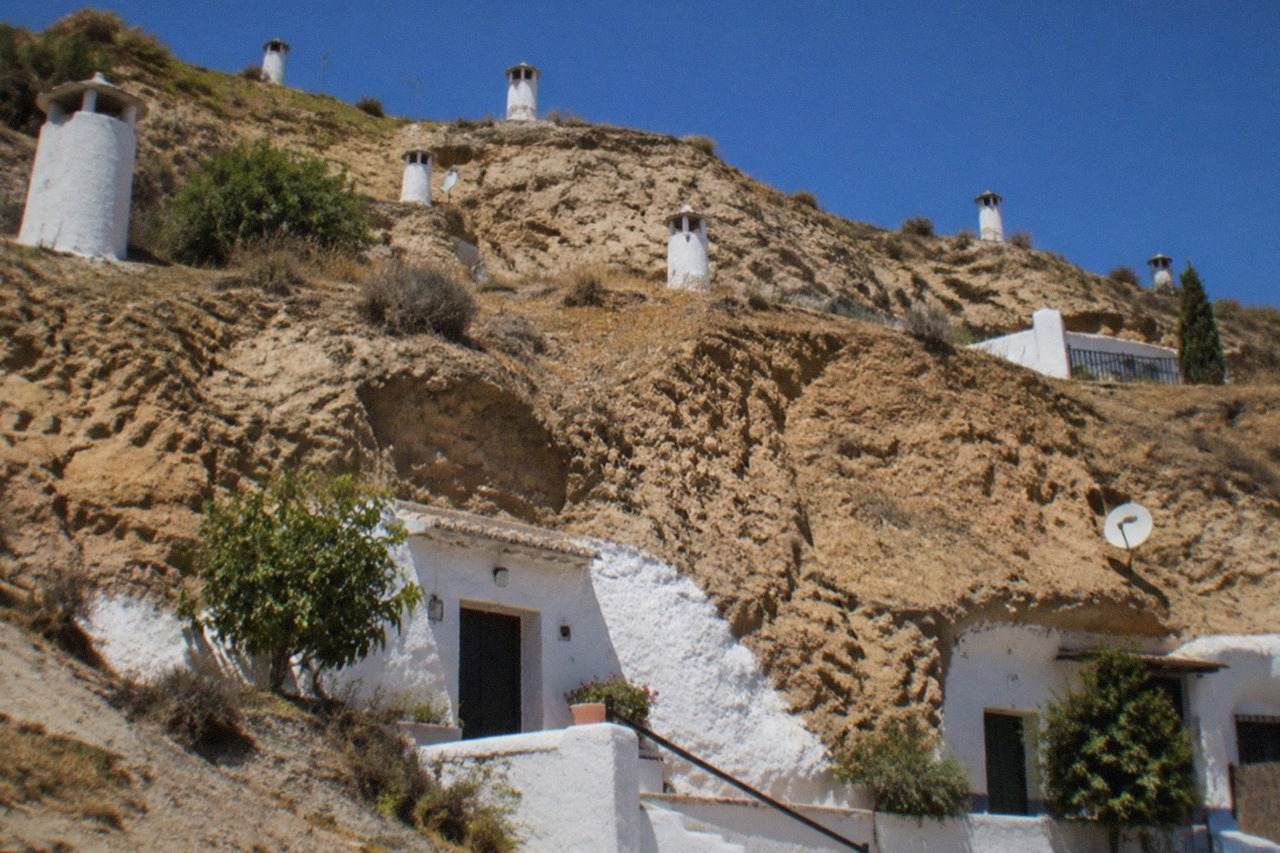 White cave house facades built into the hillside of the Sacromonte district in Granada