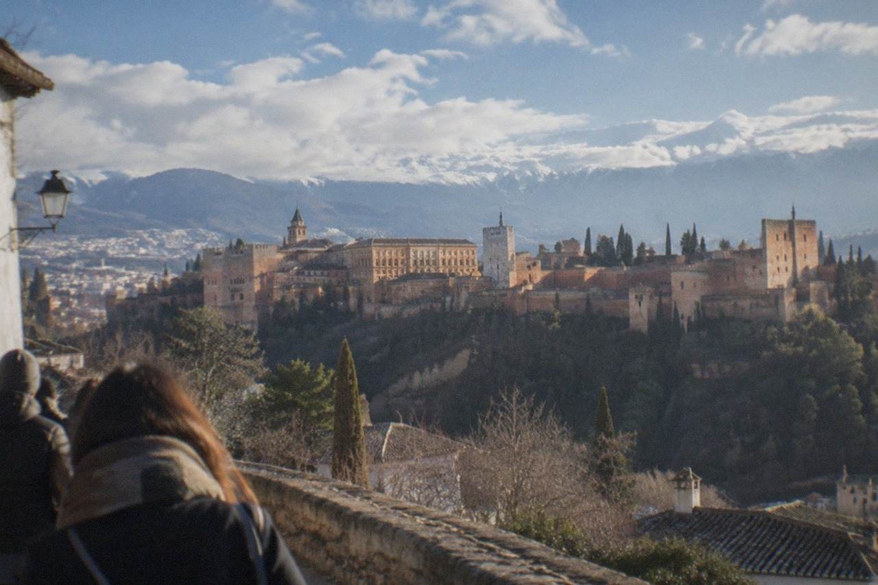 The Alhambra palace complex on its hill above Granada with snow-dusted mountains rising behind the city