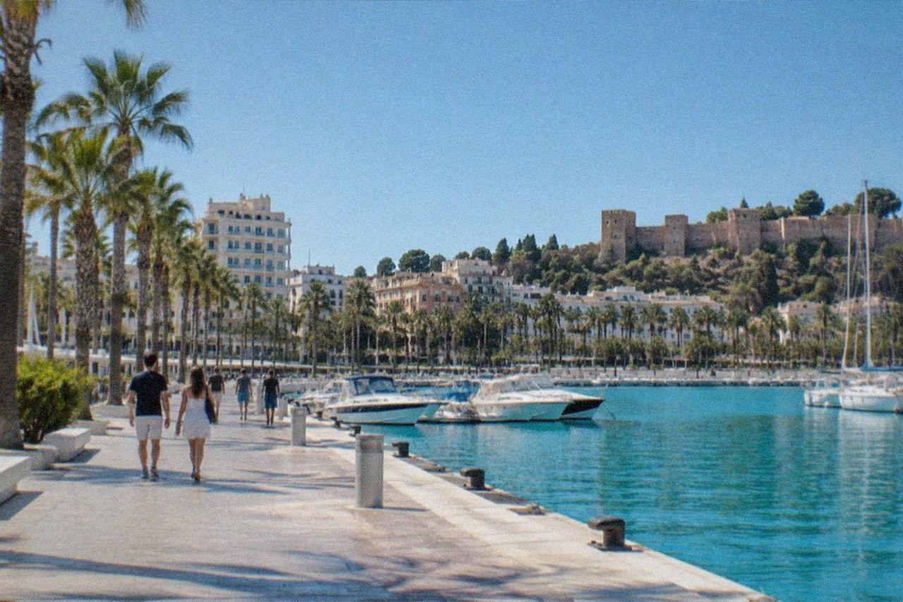 A taxi waiting on a sunny street in Málaga with palm trees and buildings in the background