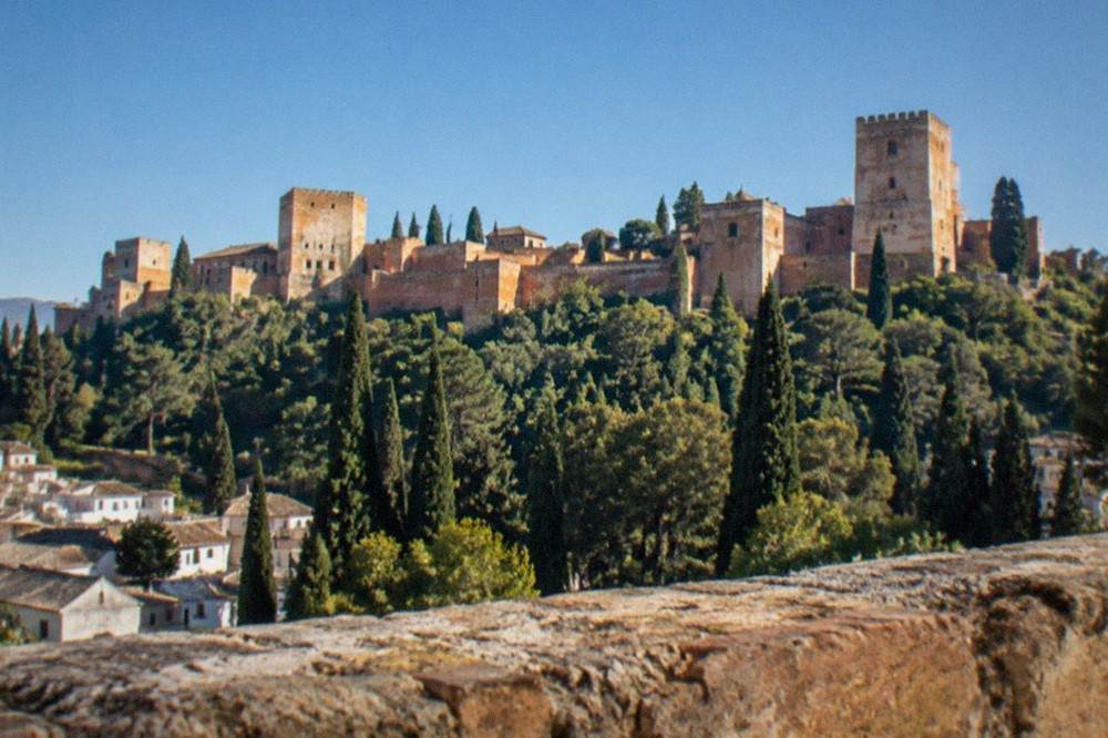 The Alhambra palace complex seen from a hillside viewpoint across the city of Granada