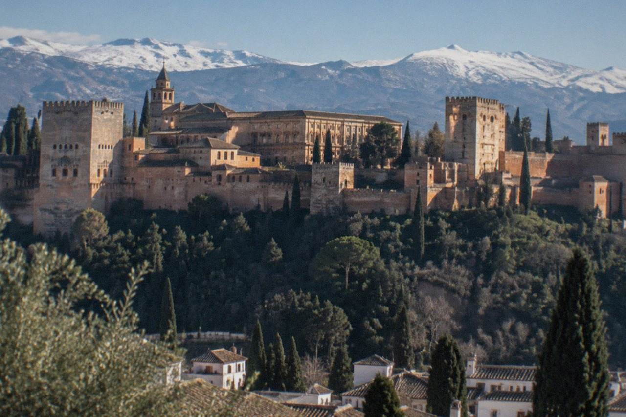 The courtyards and towers of the Alhambra complex on its hill above Granada, with the Sierra Nevada in the background