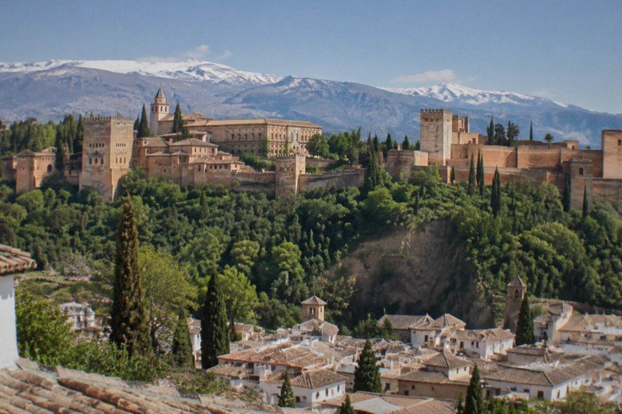 The Alhambra palace complex on its hill above the red rooftops of Granada with the Sierra Nevada in the background