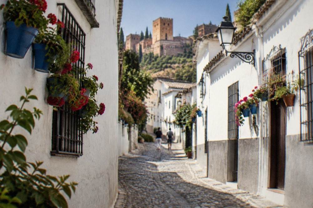 A narrow cobbled lane in the Albaicin quarter with whitewashed houses and flower pots