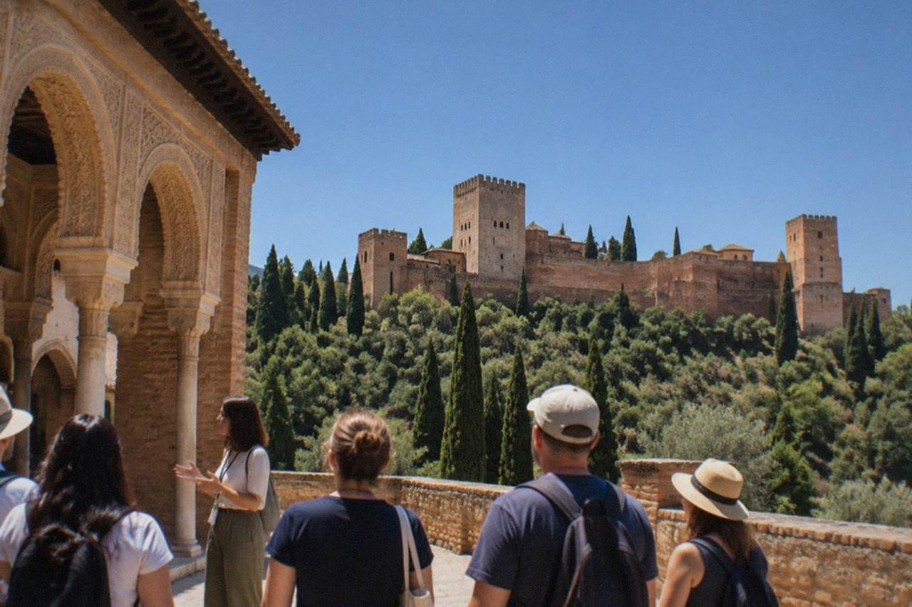 A guide speaking to a small group beside the carved arches of the Alhambra in Granada