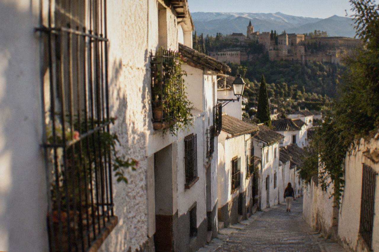 White-washed houses on a hillside street in the Albaicín quarter of Granada with the Sierra Nevada in the distance