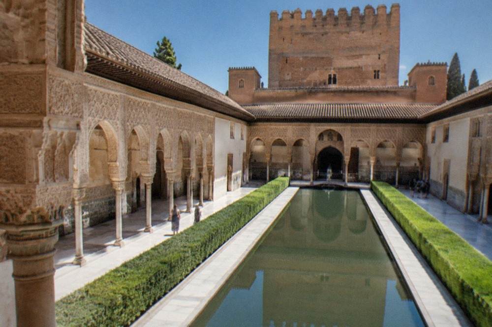 Ornate carved stonework and arched windows inside a Nasrid palace hall