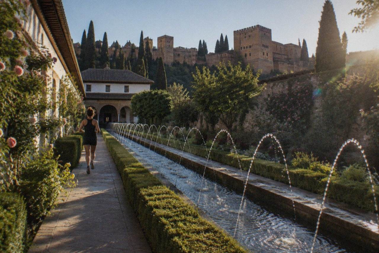 The terraced gardens and long water channel of the Generalife in Granada with the Alhambra walls in the background