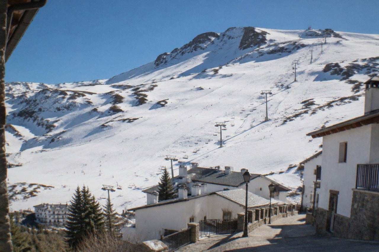 A quiet Granada street with white buildings and the Sierra Nevada mountains in the background