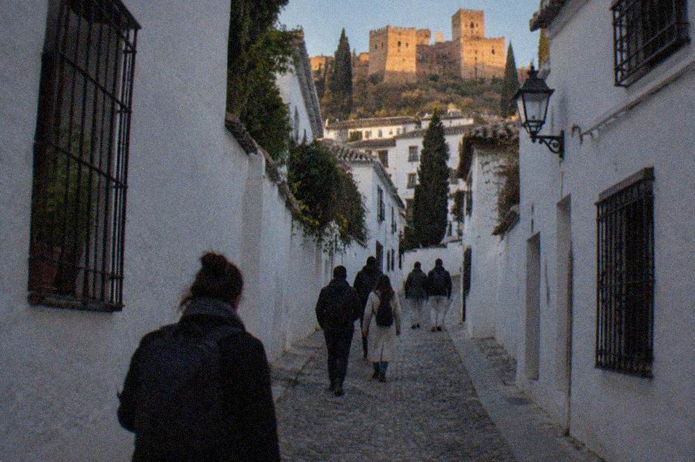 People walking along a narrow cobbled street in the Albaicin at dusk