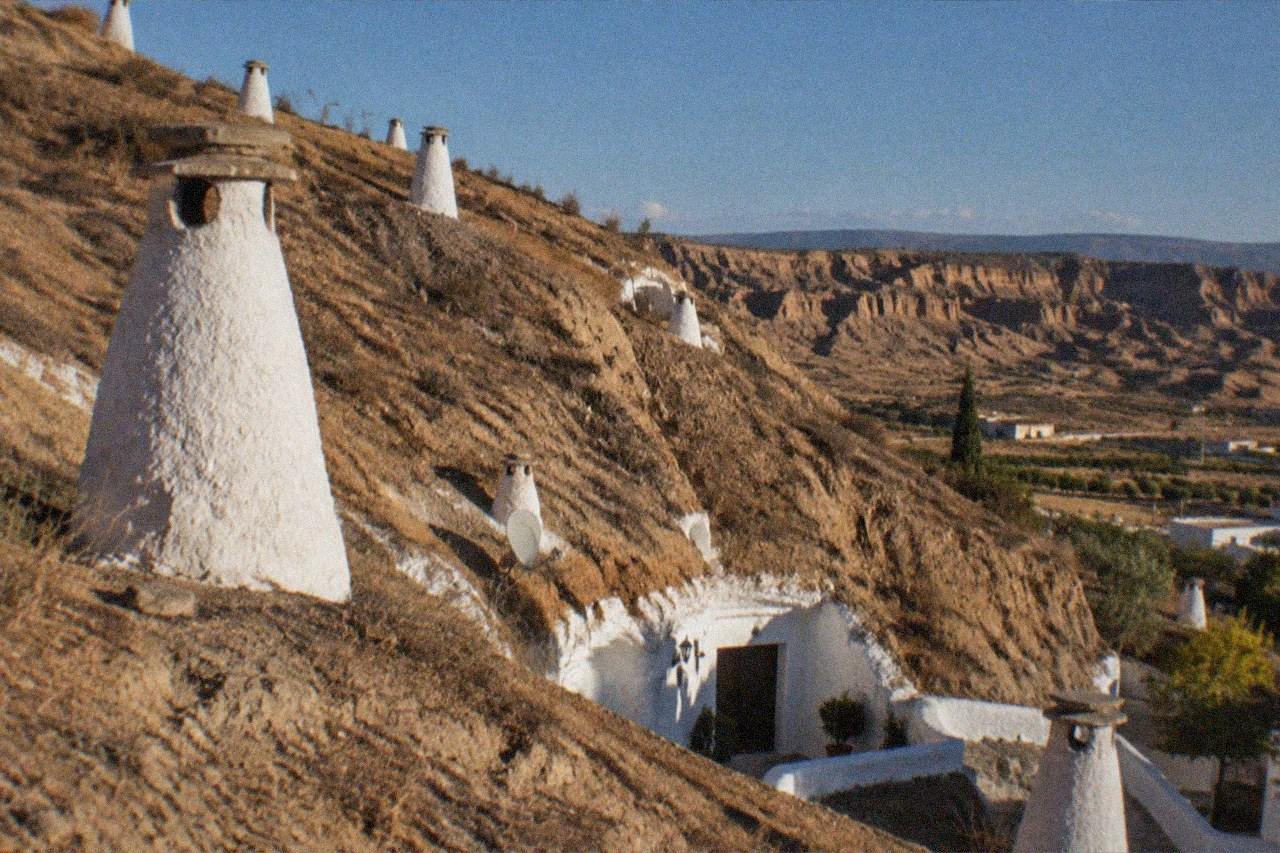 Whitewashed cave houses built into the hillside of the Sacromonte district in Granada at golden hour