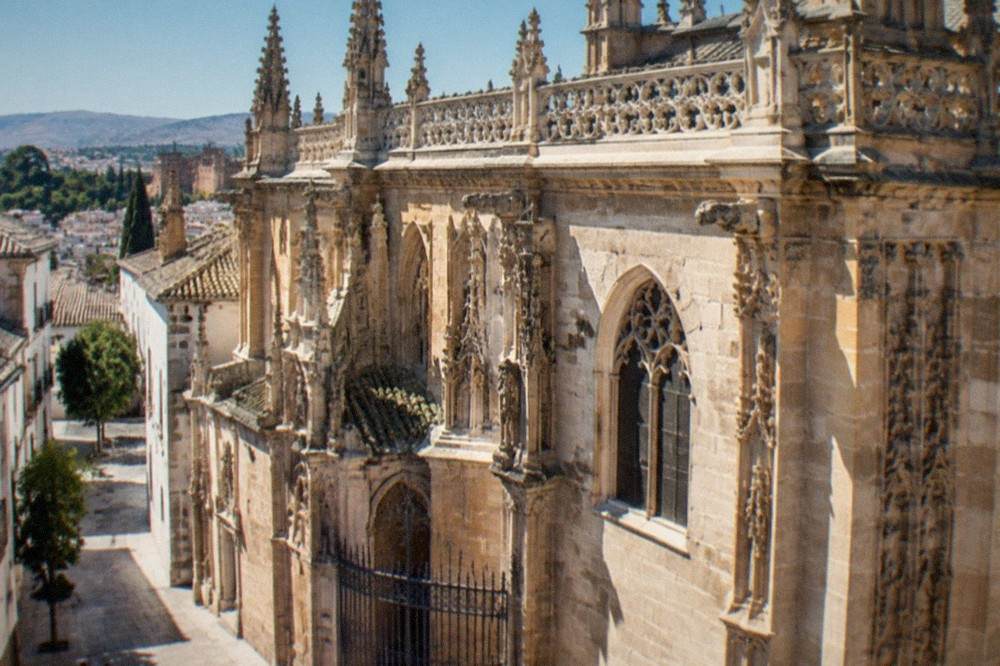The ornate interior of Granada's Royal Chapel with its carved royal tombs in the dim light.