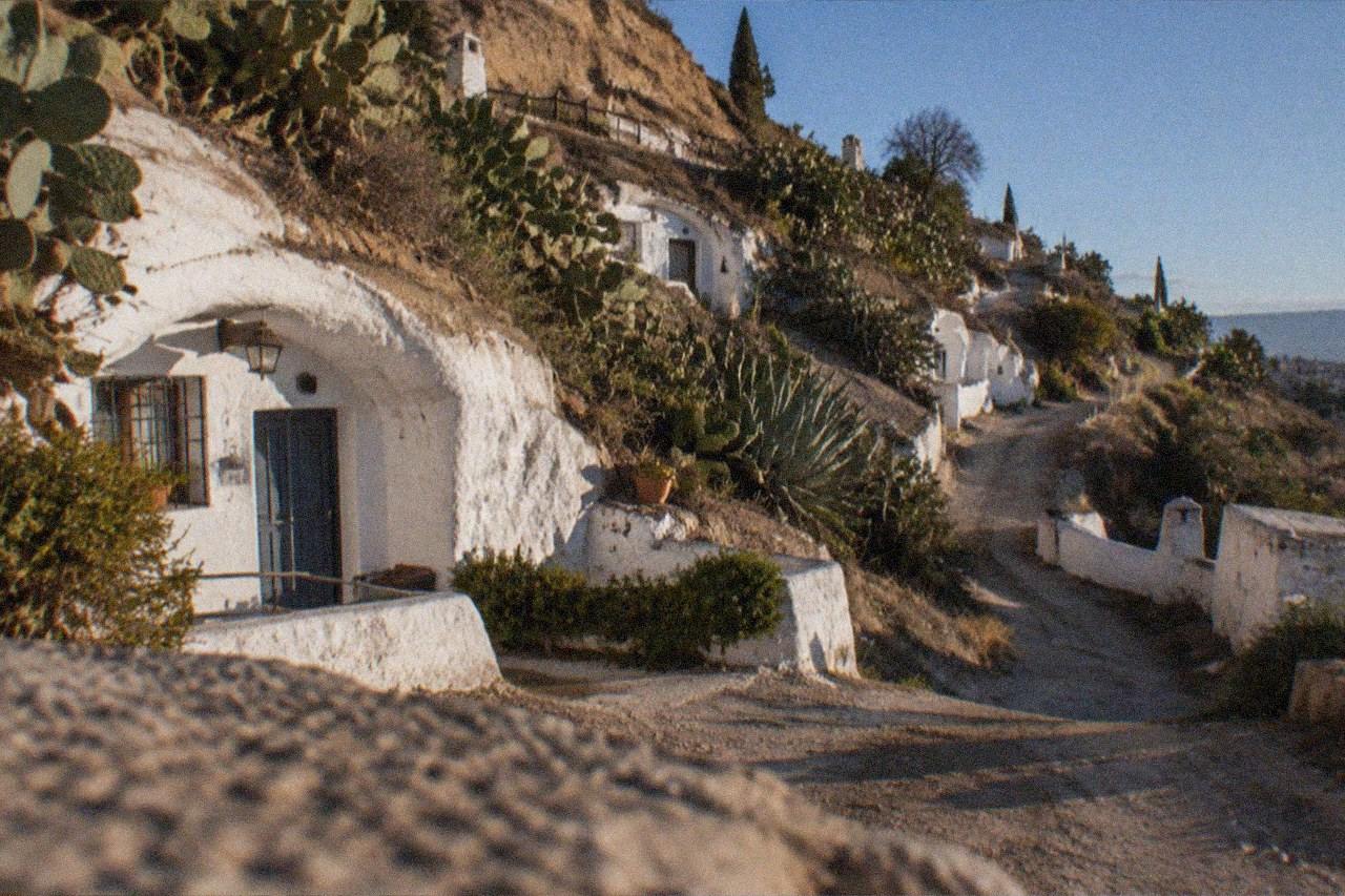 A whitewashed cave dwelling on a hillside in the Sacromonte district of Granada at dusk