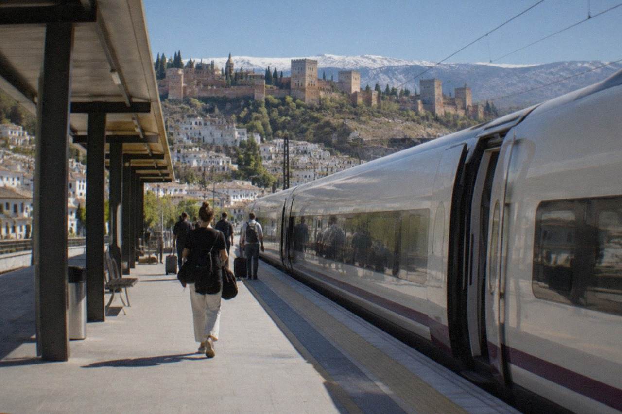 A high speed train standing at a railway platform in Spain with passengers waiting to board
