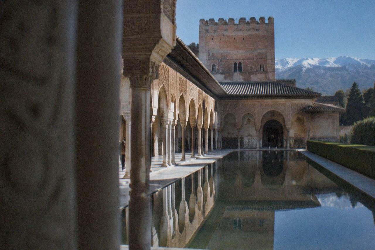 The Nasrid Palaces of the Alhambra seen from a garden terrace with the Sierra Nevada in the distance