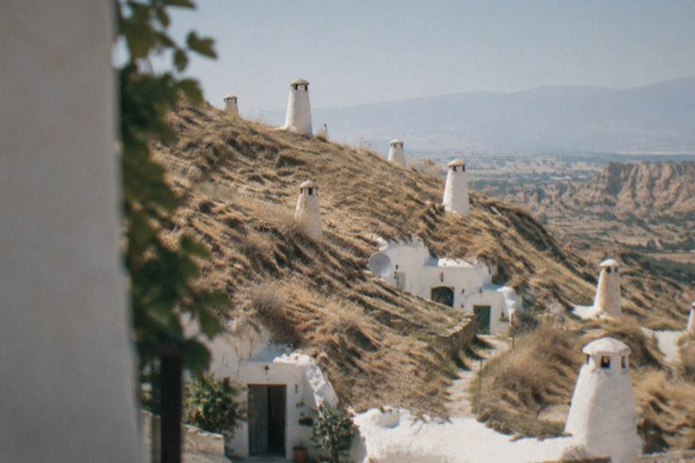 Cave house facades with white chimneys built into a hillside on the plateau near Guadix