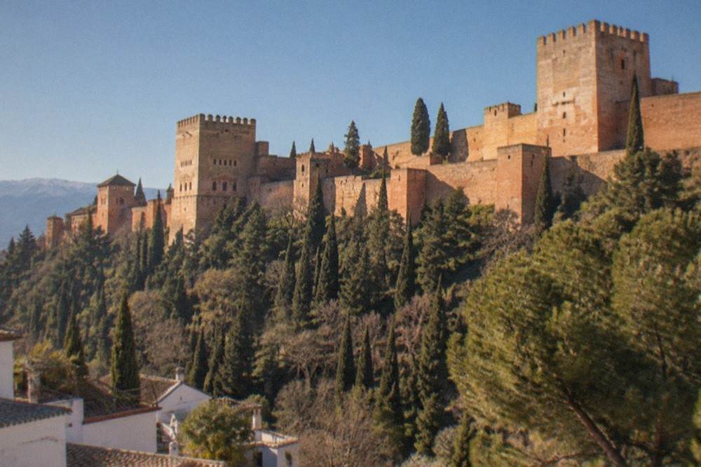 The Alhambra walls and towers above the tree-lined slopes of the Sabika hill