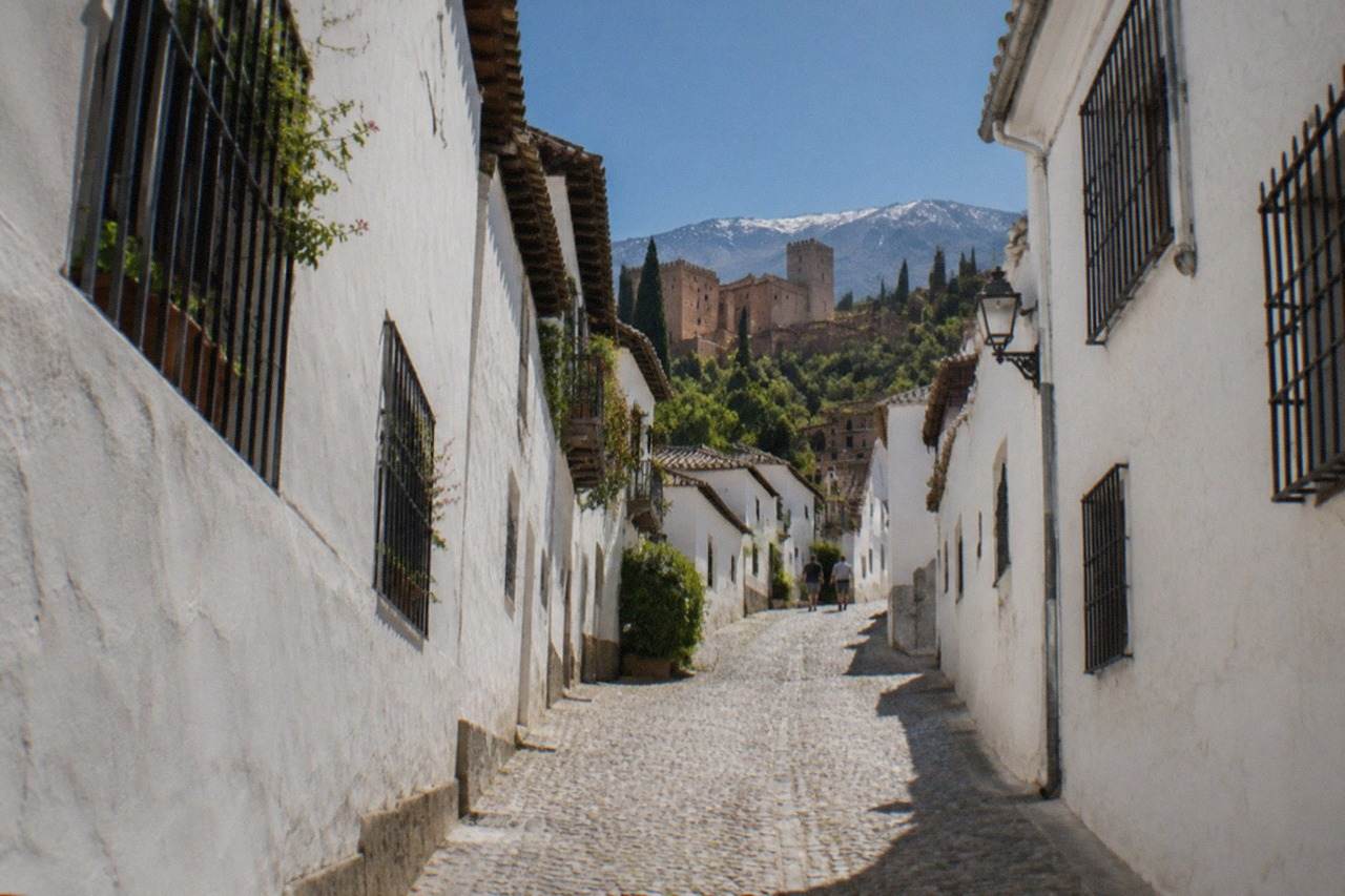 White-washed houses of the Albaicin quarter on a hillside with the Sierra Nevada mountains in the distance