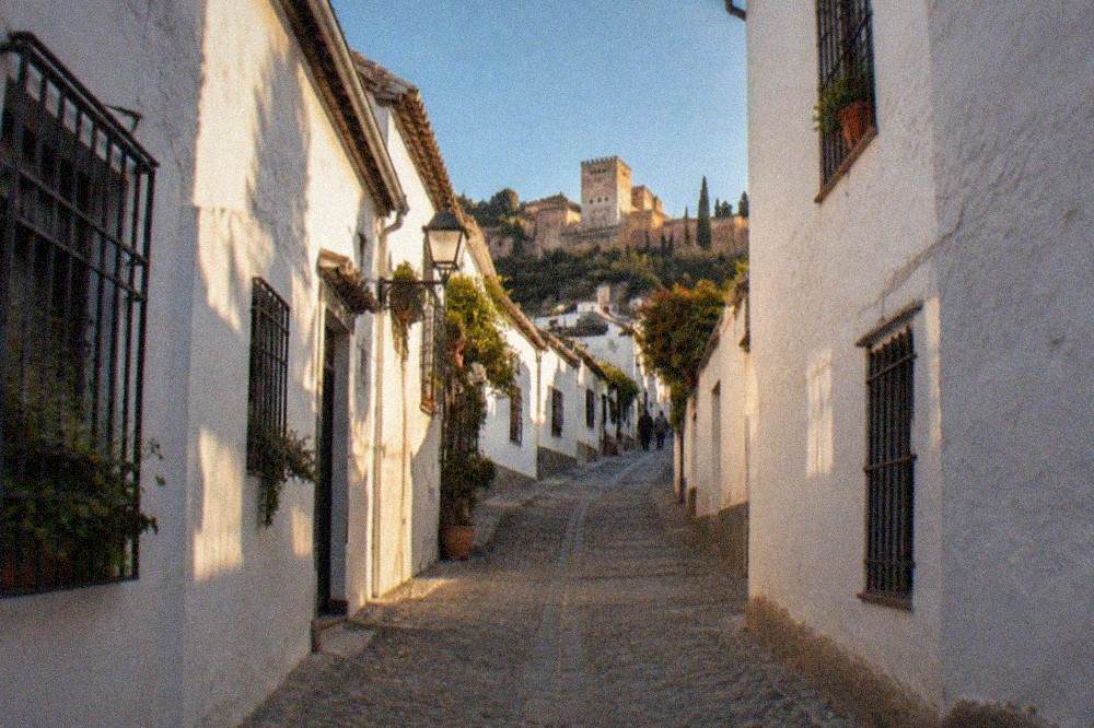 A narrow street in the Albaicin at dusk with warm light on whitewashed walls
