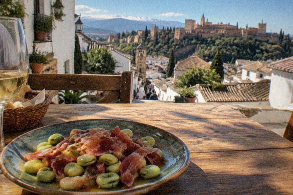 A plate of broad beans with serrano ham on a rustic wooden table in a Granada restaurant