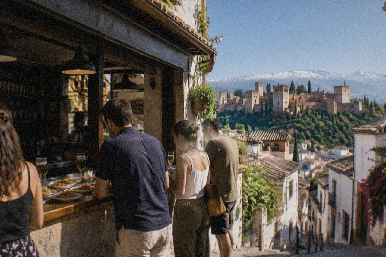 A small Granada tapas bar in the evening with people standing at the counter and plates of food on the bar top