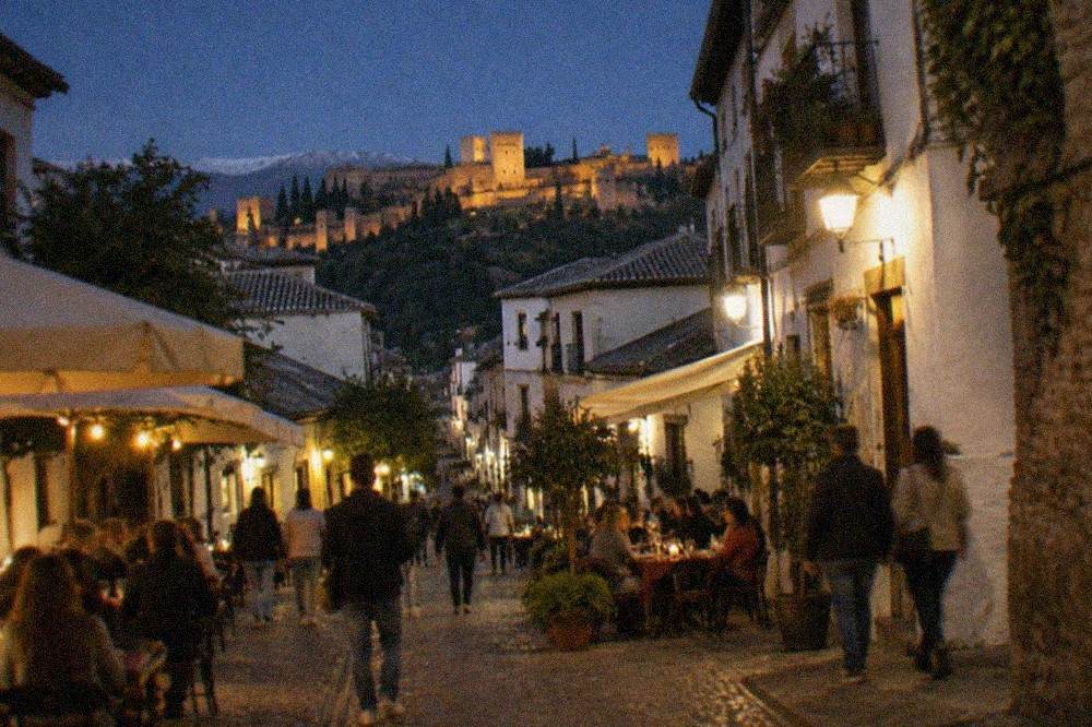 A Granada street at night with lit bar terraces and people walking between tapas venues