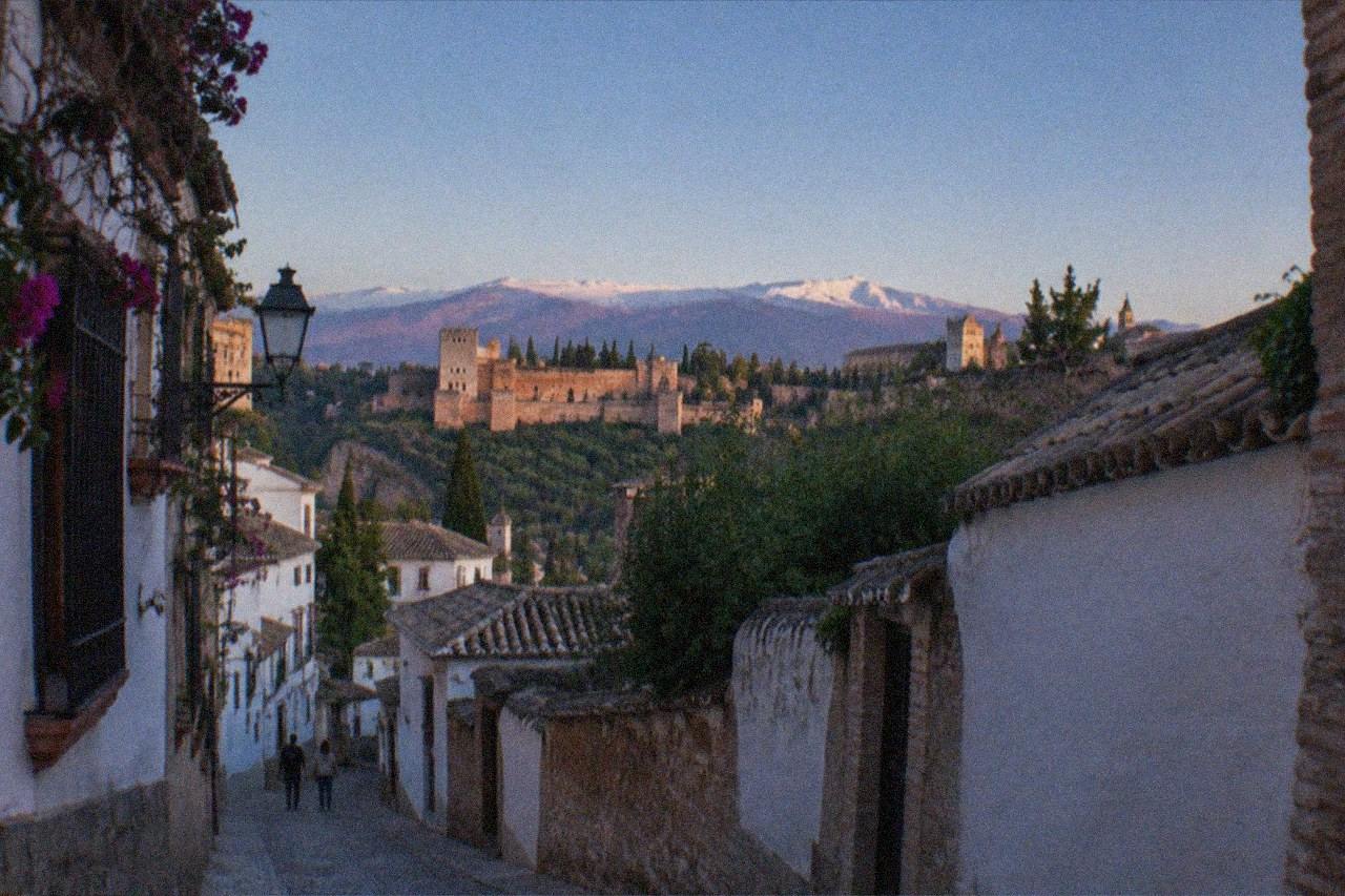 Narrow historic street in central Granada with old buildings under a clear sky