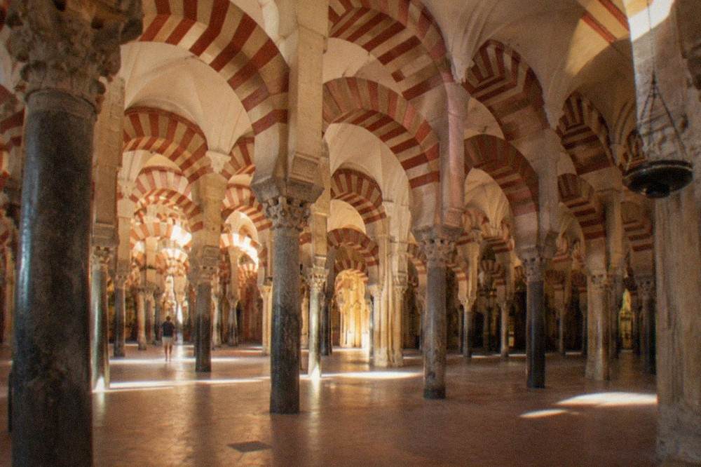 The arches and stone columns inside the Mezquita of Cordoba under warm light