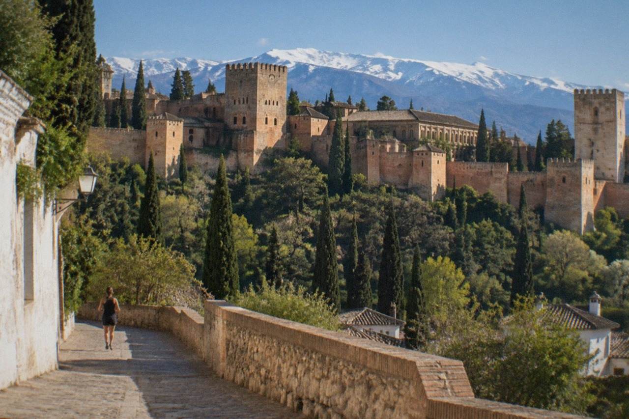 The Alhambra palace walls rising above Granada with the Sierra Nevada mountains behind