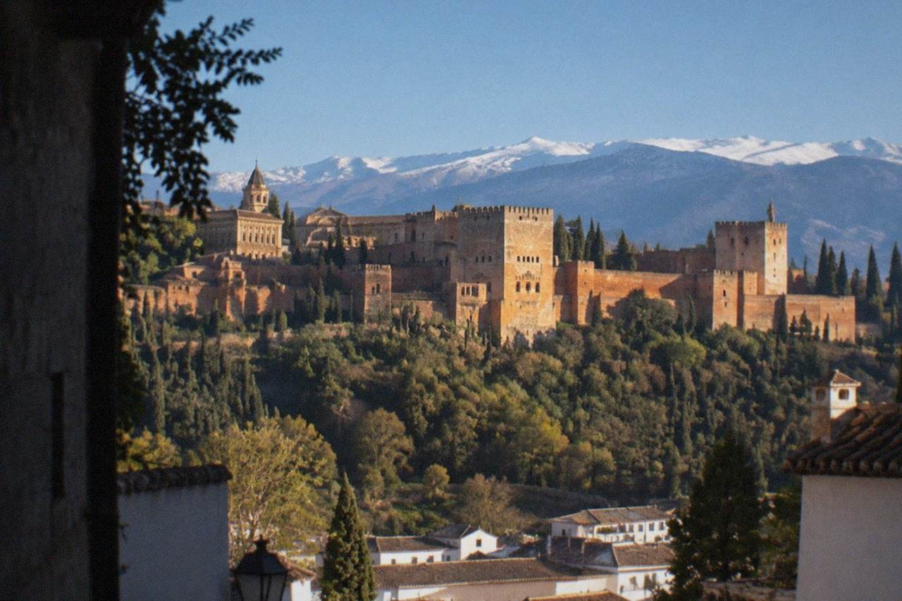 The Alhambra palace complex on its hill above the city of Granada with the Sierra Nevada in the background