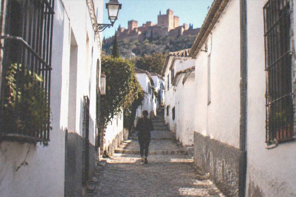 Evening street in the Albaicin with warm lamplight over stone steps and white walls