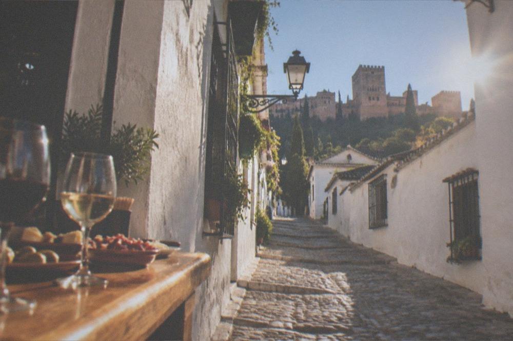 Small bar counter with glasses of wine and plates of tapas on a wooden bar
