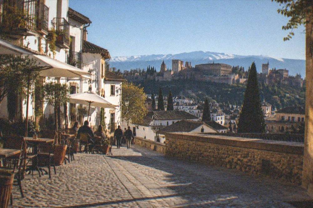 Cobbled pedestrian street in Granada with cafes and old buildings at dusk