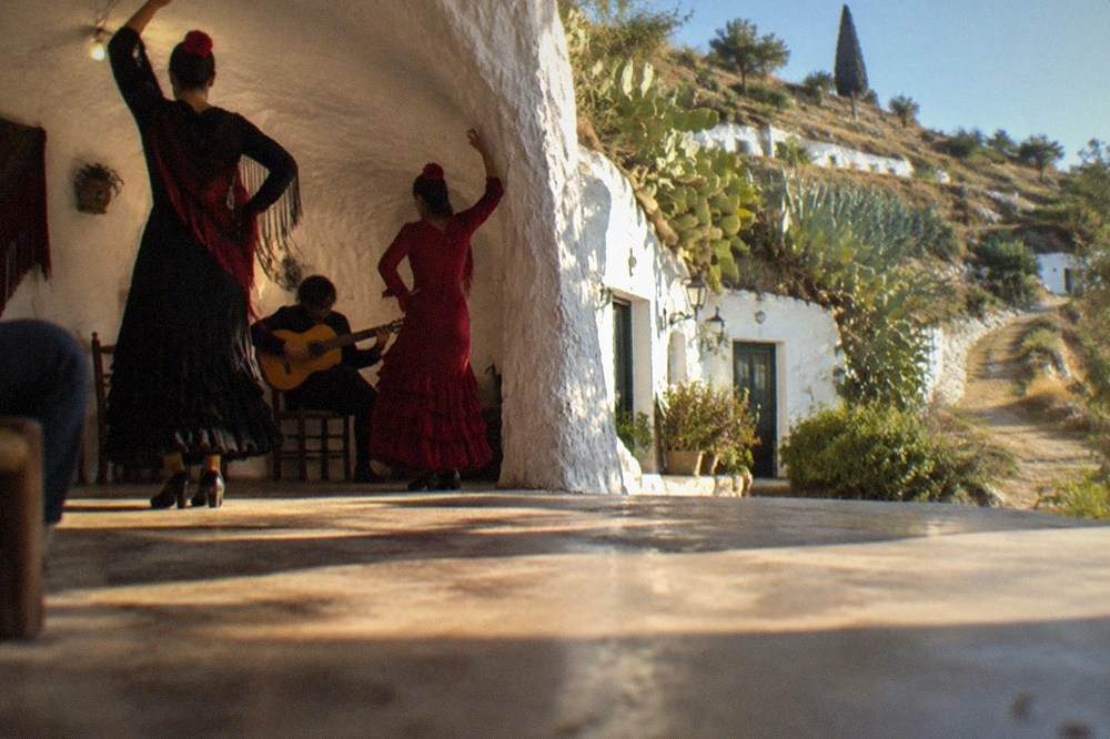 A flamenco performance inside a whitewashed cave with a guitarist and two dancers