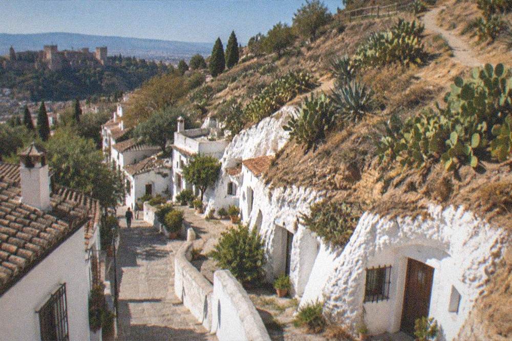 A narrow pedestrian street of white buildings climbing a hill at dusk