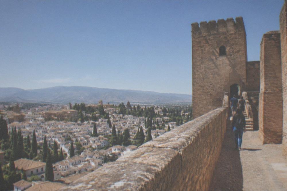 Visitors walking along a narrow stone staircase between the fortress towers