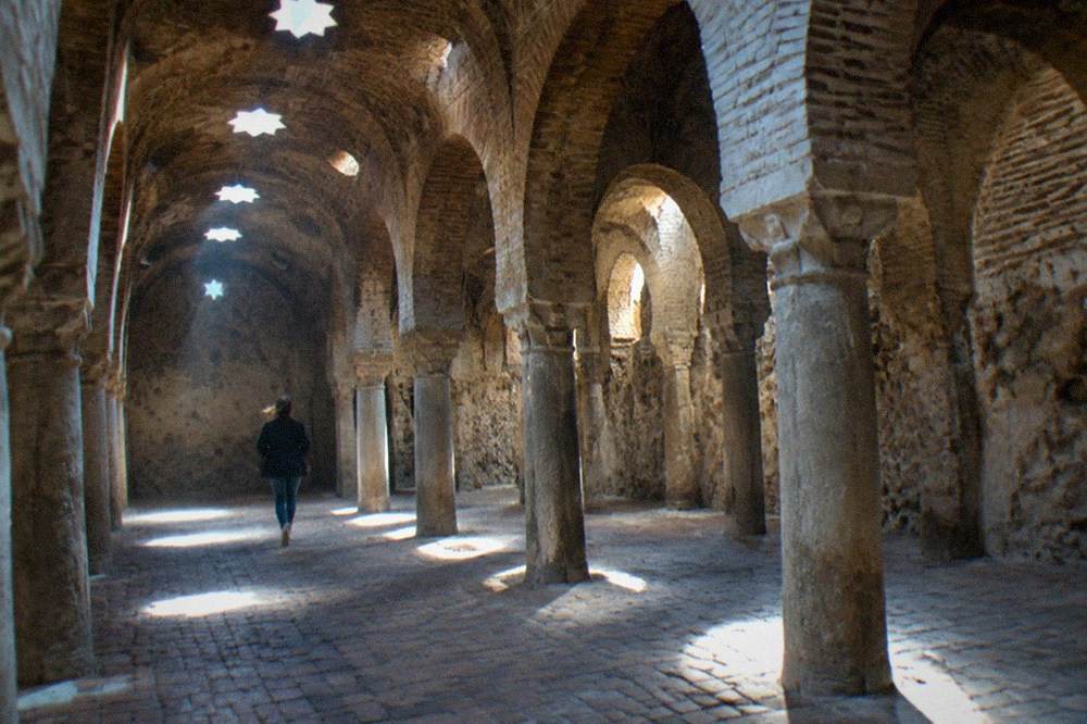 The stone facade and vaulted ceiling of an old Arab bath house beside the river in Granada