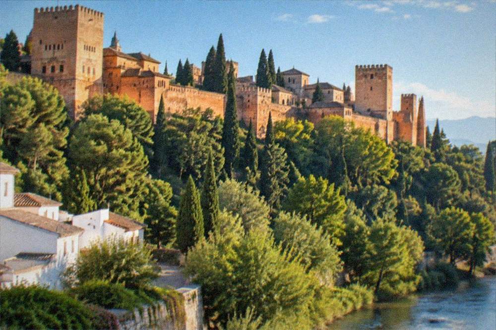 The illuminated Alhambra seen at night from across the Darro river valley