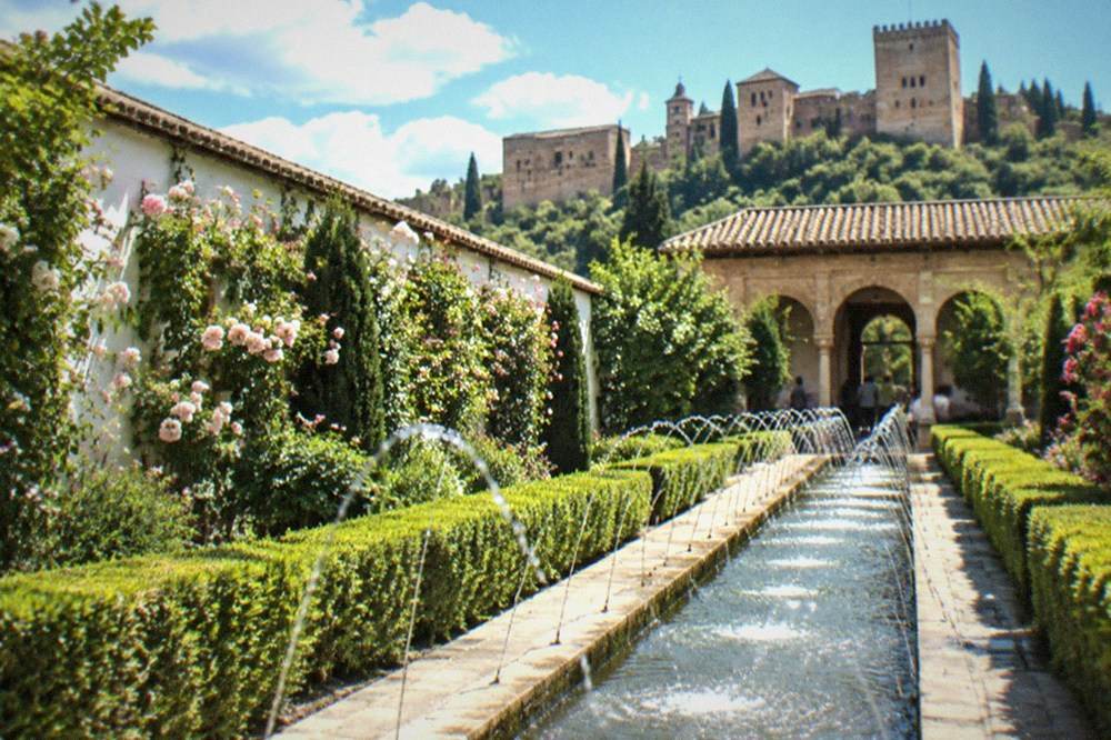 Water jets arcing over the long pool of the Patio de la Acequia with a portico at the far end