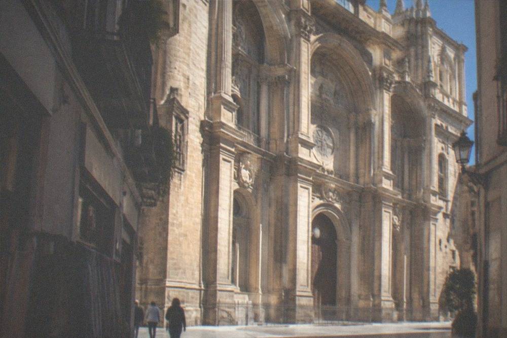 The cathedral exterior seen from a narrow street with shops nearby