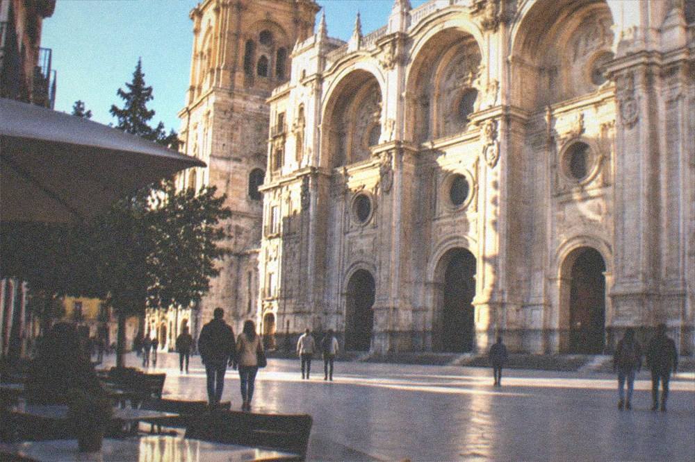 A plaza beside the cathedral with outdoor tables and pedestrians