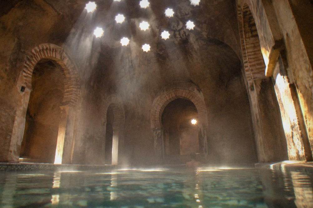 Steam room with star-shaped ceiling light holes glowing in a dim bathhouse interior