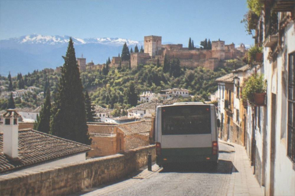 City bus on a narrow street at the top of a hill in Granada