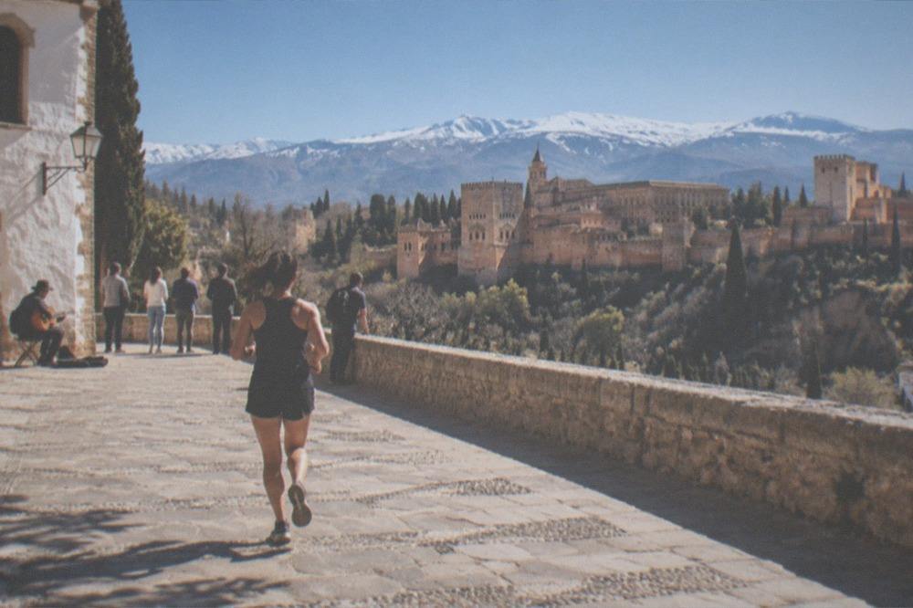 Street musician playing guitar on a plaza while people watch near a church wall