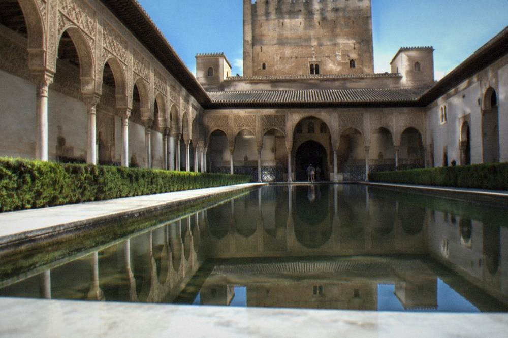A long reflecting pool mirroring the facade of the Comares Palace