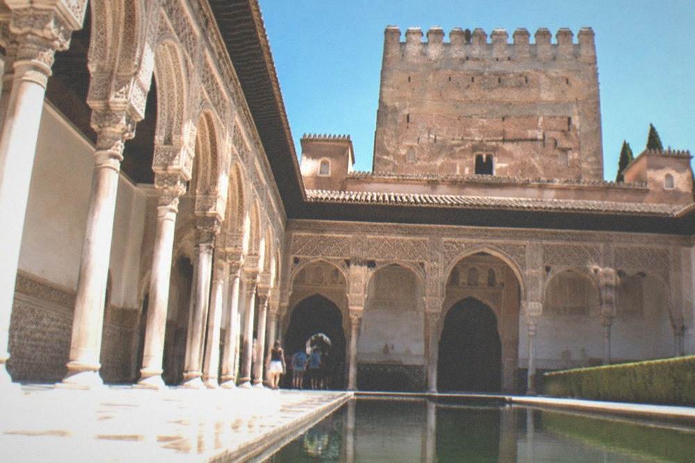 Visitors walking through a narrow carved doorway between palace halls