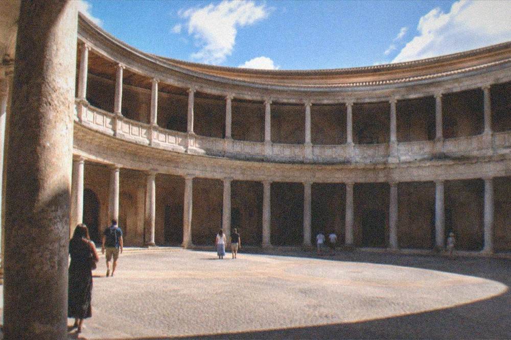 Visitors walking through the colonnade of the circular courtyard in evening light